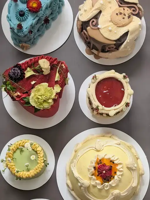 8 custom cakes layed out on grey backdrop